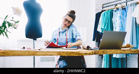 Serious woman talking on phone in atelier Stock Photo