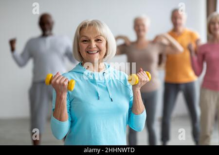 Seniors doing strength building fitness exercises with dumbbells Stock Photo