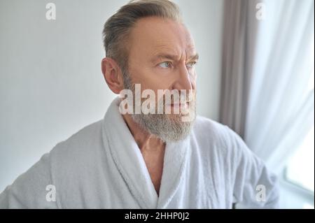 Thoughtful man in the towelling robe looking away Stock Photo