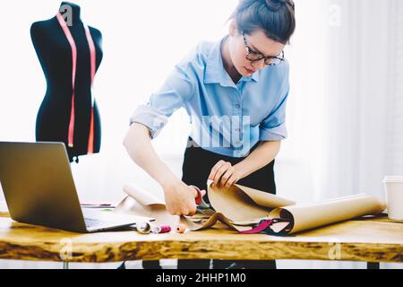 Young seamstress cutting out paper patterns Stock Photo
