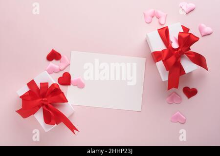 White gift boxes with red ribbon and small red decorative hearts on pink background. Top view with copy space. Valentines day or Wedding romantic conc Stock Photo