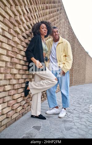 Optimistic man leaning against a brick wall Stock Photo - Alamy