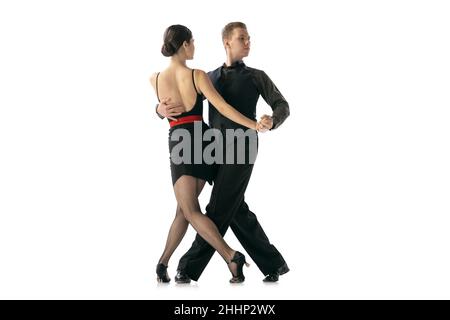 Flexible young couple dancing Argentine tango isolated on white studio background. Artists in black stage costumes Stock Photo