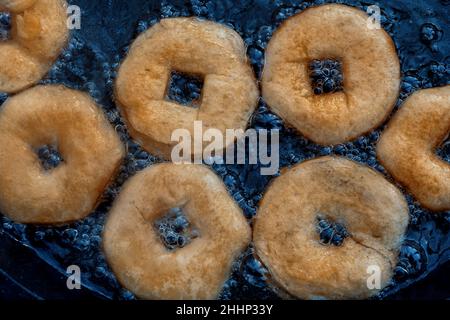 Homemade donuts frying in cast iron skillet outdoors. Stock Photo