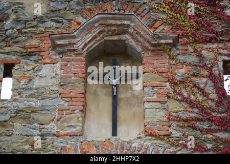 a large wooden cross hanging in the bricked up window of an old wall Stock Photo