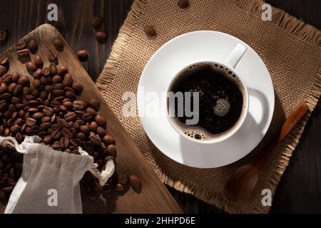 White cup of fresh hot coffee and coffee beans on the table, topview, flat lay. Stock Photo