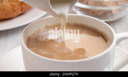 Pouring milk or cream into freshly brewed coffee, close up Stock Photo