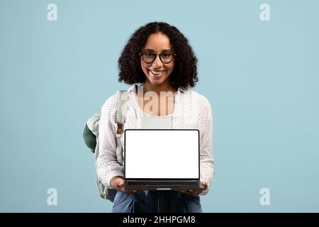 Portrait of young black female student holding laptop with blank screen for advertising website mockup Stock Photo