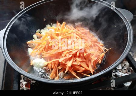 Cooking zirvak in cauldron on fire for pilaf Stock Photo