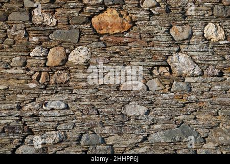 An old stone wall with strong textures and golden sunlight Stock Photo