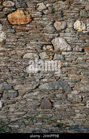 An old stone wall with strong textures and golden sunlight Stock Photo