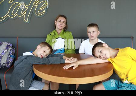 Mother with three sons waiting food in cafe Stock Photo