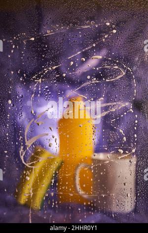 View through dirty glass. Close-up of household cleaning products and kitchen accessories. On a dark lilac background. High quality photo Stock Photo