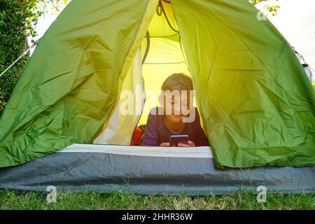 Teenager using the cell phone inside a tent Stock Photo