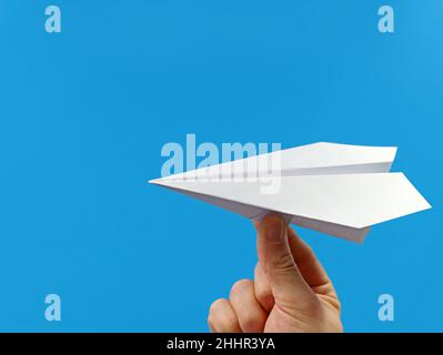 male hand holding paper plane isolated on blue background with copy space Stock Photo