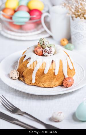 Easter cake with colorful eggs in a chocolate nest on white background. Happy Easter concept. Dessert also known as  Kuglof Stock Photo