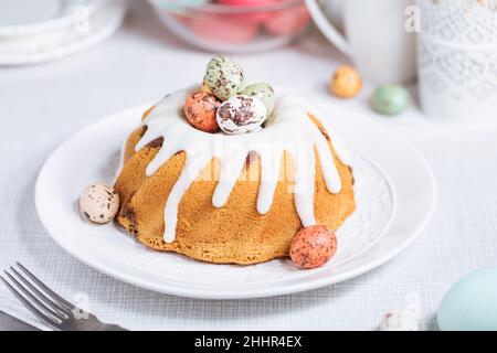 Easter cake with colorful eggs in a chocolate nest on white background. Happy Easter concept. Dessert also known as  Kuglof Stock Photo