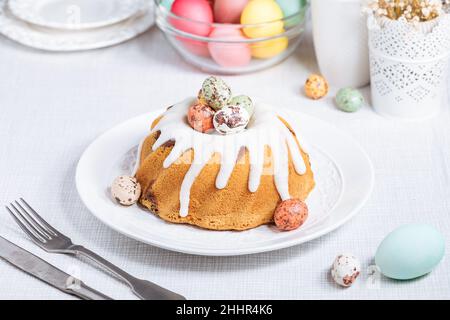 Easter cake with colorful eggs in a chocolate nest on white background. Happy Easter concept. Dessert also known as  Kuglof Stock Photo