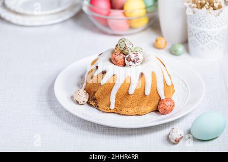 Easter cake with colorful eggs in a chocolate nest on white background. Happy Easter concept. Dessert also known as  Kuglof Stock Photo