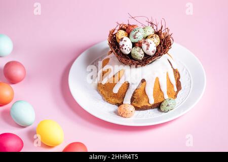 Easter cake with colorful eggs in a chocolate nest on pink background. Happy Easter concept. Dessert also known as  Kuglof. Stock Photo