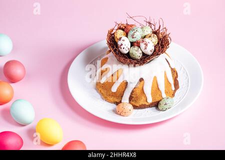 Easter cake with colorful eggs in a chocolate nest on pink background. Happy Easter concept. Dessert also known as  Kuglof. Stock Photo