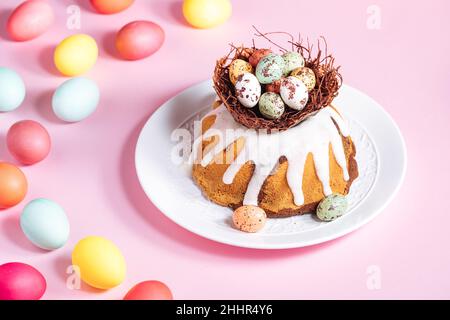 Easter cake with colorful eggs in a chocolate nest on pink background. Happy Easter concept. Dessert also known as  Kuglof. Stock Photo
