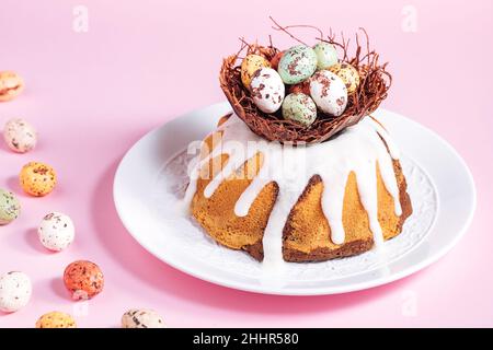Easter cake with colorful eggs in a chocolate nest on pink background. Happy Easter concept. Dessert also known as  Kuglof. Stock Photo