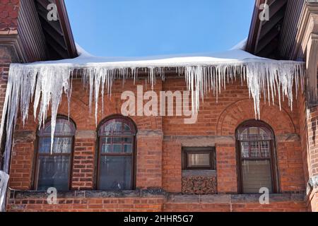 Old brick house with large icicles hanging from the roof Stock Photo