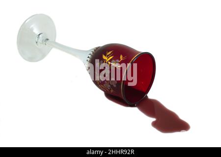 Glass of wine fell on the table. The wine has spilled. Isolated on white. Stock Photo