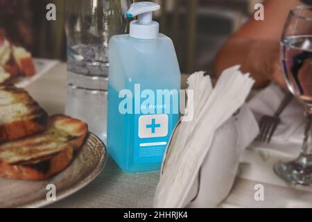 Disinfectant bottle on a table in the restaurant to prevet COVID-19 Coronavirus pandemic. Small businesses are in trouble without tourism and clients. Stock Photo