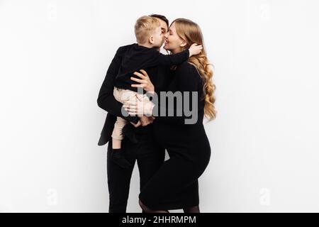 Happy family spend time together. pregnant woman, her husband and little son are talking and smiling while spending time together on white background. Stock Photo