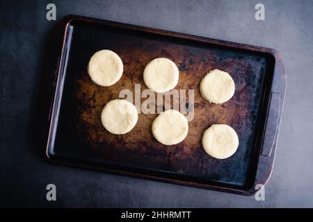 Overhead View of Uncooked Biscuits on a Sheet Pan: Raw cut out biscuit dough on a metal baking pan Stock Photo