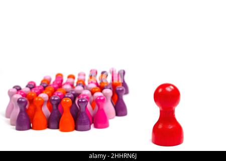 Lots of colorful small wooden cones and a large red wooden cone against a white background Stock Photo