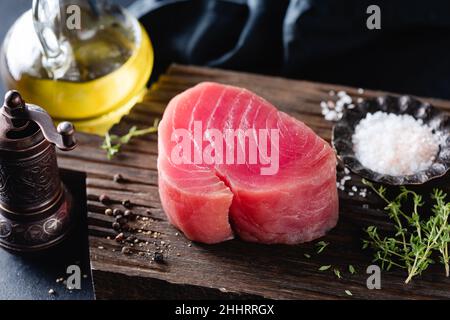 Raw pink tuna fillet and spices on a wooden background. Fish steak ready for cooking Stock Photo