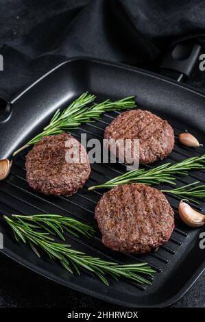Grilled burger meat patties with spices on grill pan. Black background. Top view Stock Photo