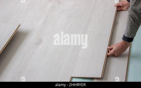 Workers' hands install a wooden laminate floor. Home renovation with wooden floors with measurements. Stock Photo