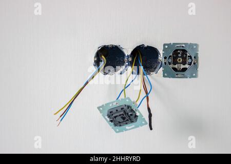White Uk plug sockets being plugged into with a black plug and male arm Stock Photo