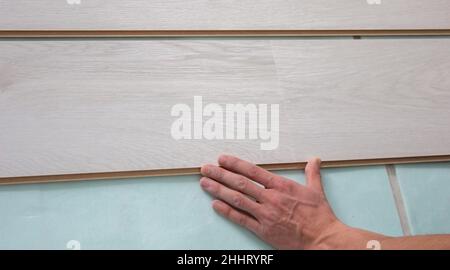 Workers' hands install a wooden laminate floor. Home renovation with wooden floors with measurements. Stock Photo