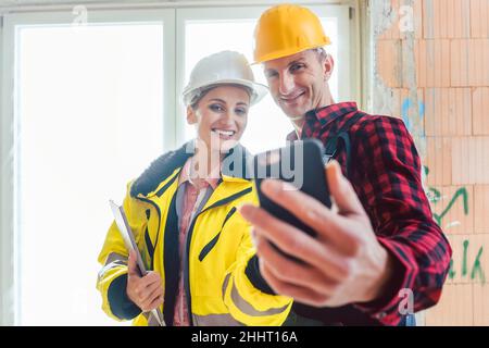 Female construction engineer and male worker taking selfie Stock Photo