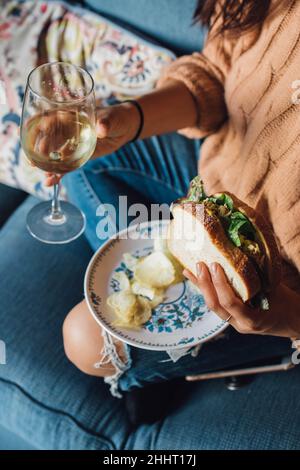 woman holding tuna sandwich while sitting on couch Stock Photo