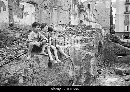 Scenes in Naples, southern Italy showing local children playing on a pile of rubble. Circa 1955. Stock Photo