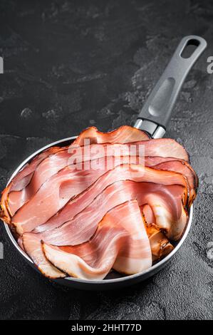 Cooking of Black Forest Ham in skillet. Black background. Top view Stock Photo