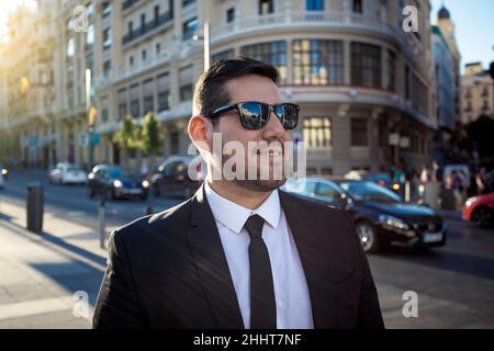 elegant and smiling dark-haired man through the streets of Madrid Stock Photo