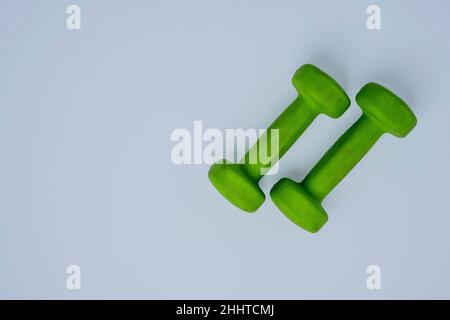 A pair of light green small dumbbells on a white background, fitness, healthy lifestyle. Stock Photo