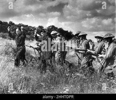 Home Guards are given instructions on how to defeat enemy tanks during training at the Home Guard School of Instruction. Here they are pictured leading off the tank crew after capturing the vehicle that was caught in an anti-tank trap. 20th July 1941. Stock Photo