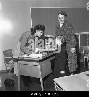 Teacher greets a new addition to her class at  South Mead School, Southfield, Wimbledon. 14th January 1954 Stock Photo