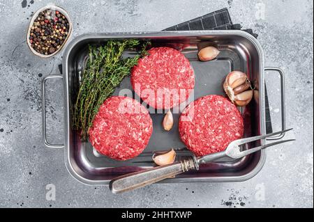 Fresh Raw Ground mince beef meat Hamburger steak patty in a steel tray. Gray background. Top view Stock Photo
