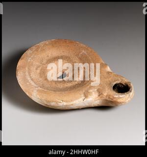 Terracotta oil lamp Roman, Cypriot Loeschcke Type 4. Mold-made. Discus: indistinct wreath around central filling hole, with small taenia opposite nozzle. Plain shoulder. Volutes flanking nozzle. On left side of body: raised, molded letters in retrograde: ZW. Slightly raised base ring and flat base.. Terracotta oil lamp. Roman, Cypriot. Terracotta. Early Imperial. Terracottas Stock Photo