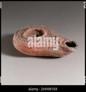 Terracotta oil lamp 3rd century A.D. Roman Mold-made, with ring (?) handle; Small, flat discus decorated with a seven-petalled rosette and a single, central filling hole, and surrounded by a raised circle; on horizontal shoulder, pattern of close-set raised dots, with a line of three circles at front; a raised cross with central dot on top of nozzle, and large wick hole. Undefined, flat base, with indistinct, vertical herring bone pattern as the maker's mark.Body complete, but almost all of handle missing.. Terracotta oil lamp. Roman. 3rd century A.D.. Terracotta; mold-made. Late Imperial. Ter Stock Photo