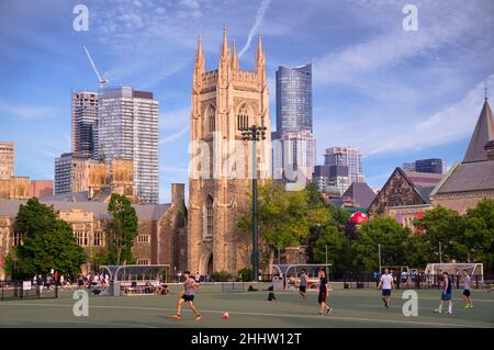 Toronto, Canada - 08 19 2018: Students playing soccer on green field of University of Toronto St George Campus in front of memorial Soldiers Tower lit Stock Photo